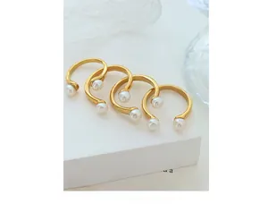 Set of four U-shaped gold rings with freshwater pearls on white geometric display stand
