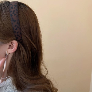 Detail of leopard print headband with heart patterns and matching pearl earrings