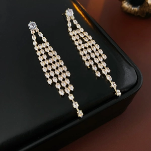 Detail view of gold-plated tassel earrings with sparkling zircon stones on black leather