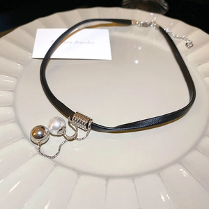 Detail of a black leather choker with silver metal accents and white pearl pendant