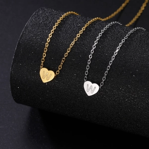 Macro shot of gold and silver heart necklaces with letter W on black cylinder