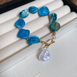 Macro shot of blue shell bracelet with baroque pearl pendant and gold T-bar closure