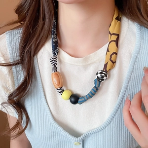 Vue détaillée d'un collier bohème en tissu et perles de bois aux motifs floraux et textures