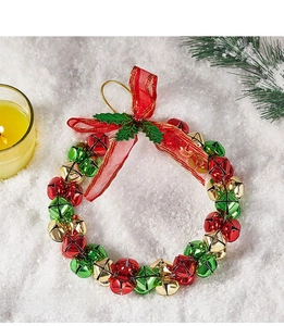 Christmas wreath with red green gold metal bells and a silk bow on snowy background