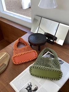Detailed shot of orange and green woven tote bags with solid bases on a wooden table