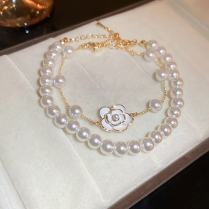 Detail of double-layer pearl bracelet with camellia flower pendant on velvet jewelry box