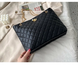 Detail of black quilted tote bag with gold chain strap and butterfly buckle decoration