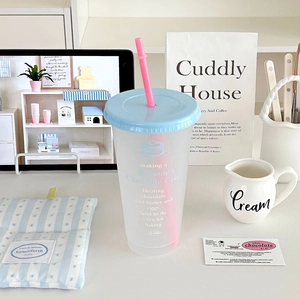Close-up of matte plastic straw cup with recipe prints on a cream desk setting