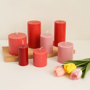 Group of seven pink and red pillar candles on a wooden tray with a minimalist aesthetic