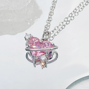 Collar de corazón rosa con anillo de Saturno plateado sobre fondo de cristal