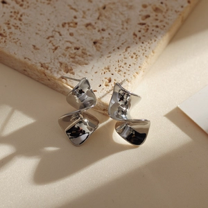 Detailed view of silver spiral metal earrings with a twisted ribbon geometric design