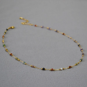 Close-up of minimalist gold necklace featuring colorful natural stone beads and tiny gold spacers