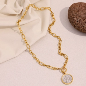 Detailed close-up of 18K gold-plated angel coin necklace on a textured stone