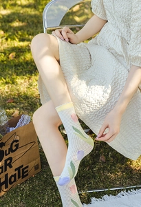 Detail of white mesh crew socks with tulip patterns worn on a sunny green lawn