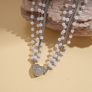 Détail d'un collier multicouche avec perles et pendentif coeur orné de strass