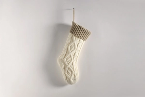 Close-up of cream knitted Christmas stocking with khaki rib cuff and cable stitch texture