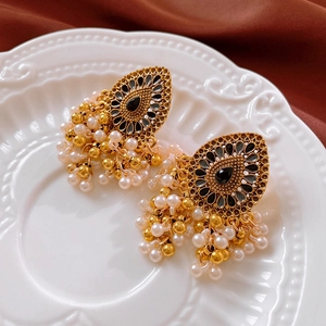 Macro shot of vintage gold tassel earrings with black stones and white pearl drops