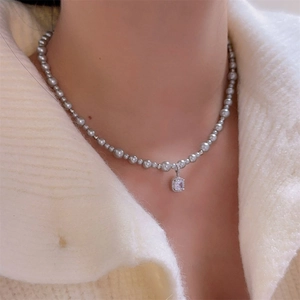 Detail of elegant pearl necklace with square crystal pendant worn on a model