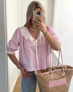 Detailed close-up of pink plaid shirt with white lace collar and delicate puffed sleeves