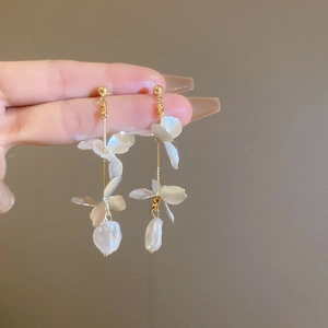 Detail of long floral tassel earring with white petals and baroque pearls on golden chain