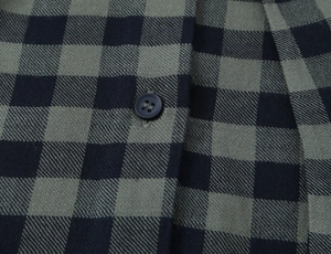 Macro detail of dark green plaid shirt showing fabric texture and matte button