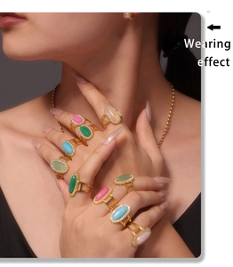 Dettaglio di anelli d'oro con zirconi multicolori e pietre naturali indossati con collana