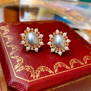 Macro shot of vintage gold stud earrings with oval blue center stone and pearl trim
