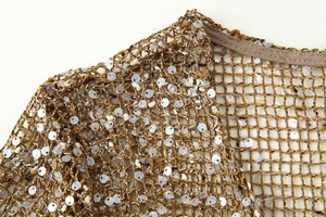 Vue détaillée du tissu en maille dorée avec paillettes argentées sur l'épaule et le col