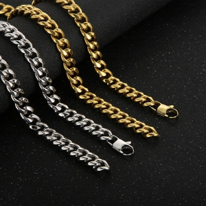 Macro shot of silver and gold Cuban link chains with secure lobster clasps on dark background