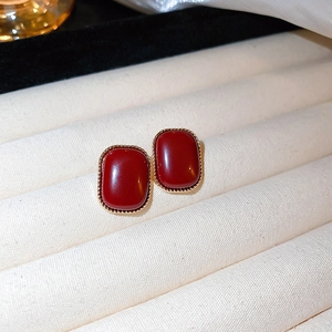 Macro shot of red heart stud earrings on beige textured fabric with soft background