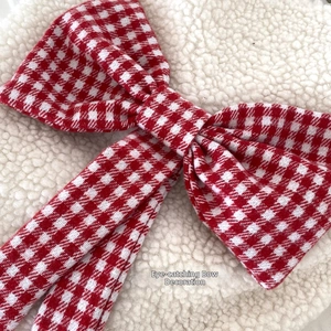 Detail of red and white checkered bow ornament on soft white plush lamb wool fabric