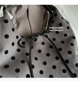 Detail of gray knitted bucket bag with black polka dots and shiny leather bow accent