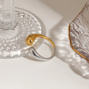 Detail of minimalist two-tone teardrop open ring in polished gold and silver finish