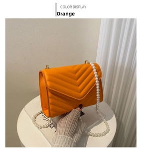Detail of orange V-quilted leather crossbody bag featuring a large pearl chain strap