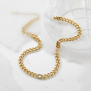 Golden Cuban link chain necklace with a round clear zircon pendant on a white background