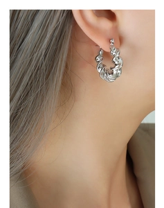 Close-up of model wearing silver twisted textured C-shaped hoop earrings in steel