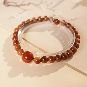 Detailed view of red agate bracelet with dark brown beads and vintage gold spacers
