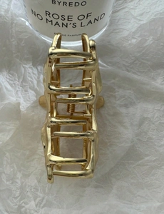 Detailed close-up of a gold wave-shaped metal hair claw clip with a glossy finish