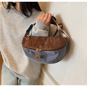 Detail of half-moon crossbody bag showing nylon and PU patchwork with dual zipper closure