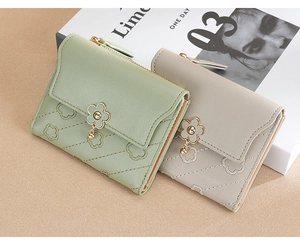 Detail of quilted leather mini wallets with flower charms in mint green and beige
