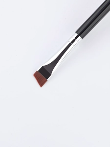 Macro view of double-ended angled eyeliner and eyebrow brush with synthetic bristles