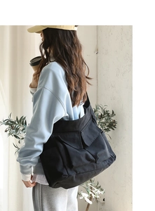 Side view of black canvas messenger bag with multi-pocket design on model in daily scene