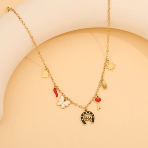 Close-up of gold stainless steel necklace with boot and bow charms on beige stand