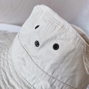 Détail du chapeau de soleil beige avec œillets métalliques et boutons-pression latéraux