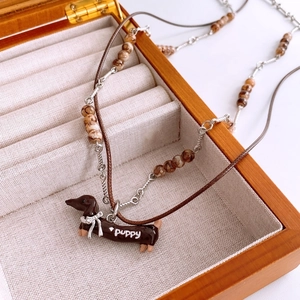 Detailed close-up of brown dachshund puppy pendant on wax cord and silver bead chain