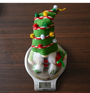 Detail view of a plush Christmas gnome gnome weighing 164.7g on a silver digital scale