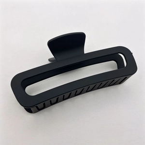 Detailed view of large black matte rectangular hair claw clip on soft fabric background