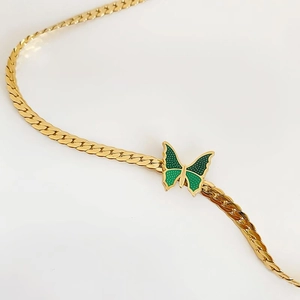 Collar dorado vintage con colgante de mariposa verde sobre fondo blanco puro