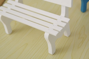 Close-up of a miniature white wooden bench for dollhouse decor and photography props