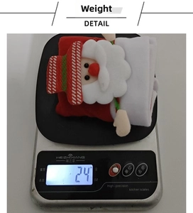 Detail view of a 24g lightweight Christmas Santa Claus fabric hanging ornament on a scale